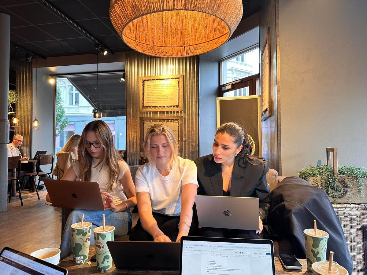 Tre studerende arbejder sammen på en café